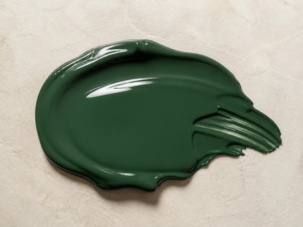 Realistic forest green gloss wall paint sample on a neutral mineral surface